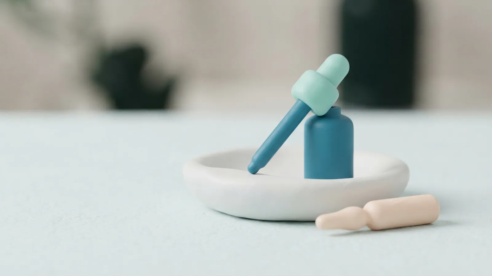 A dropper bottle and an unlabelled ampoule in a ceramic dish with soft light.